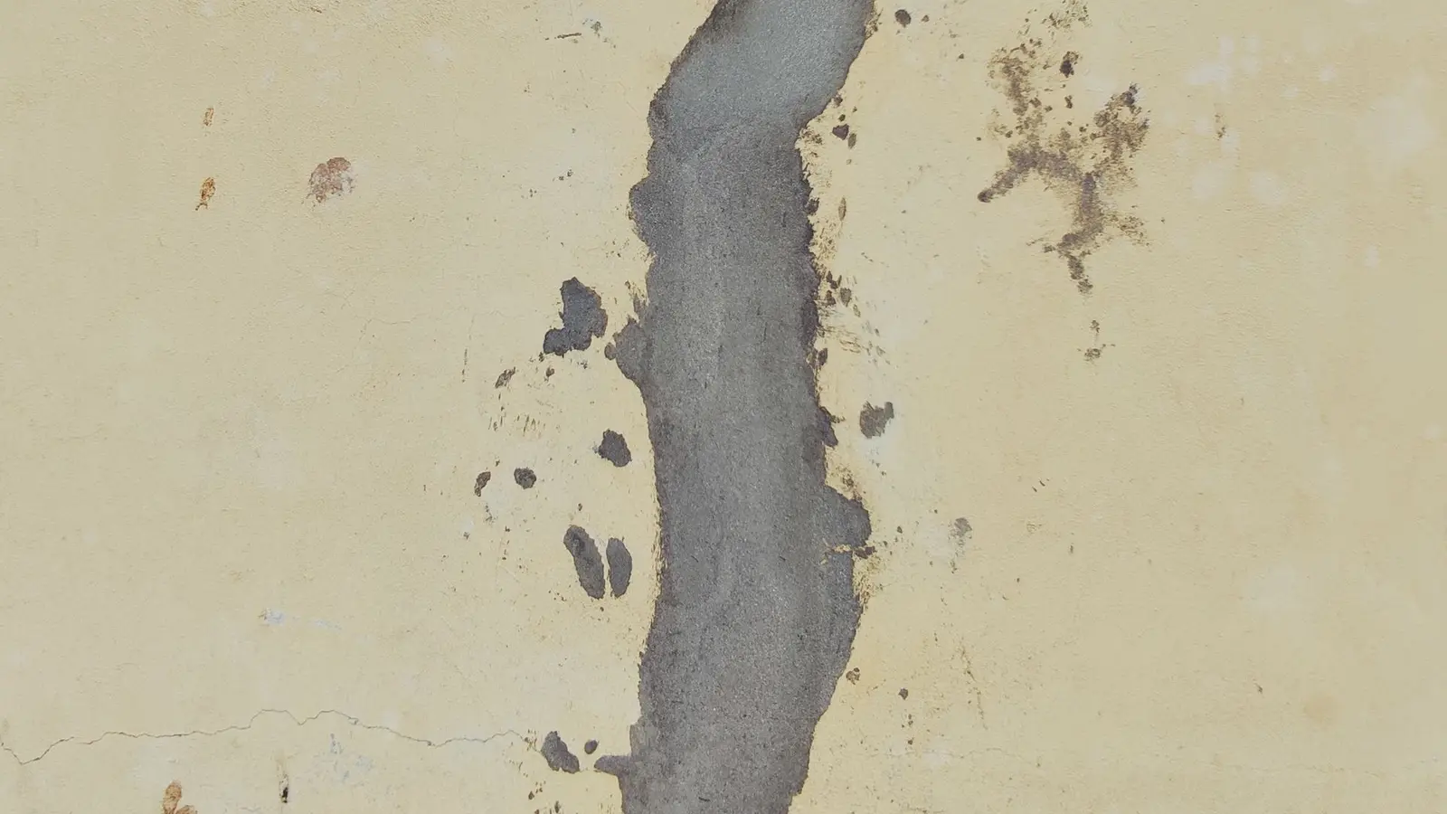 Long jagged crack filled with gray patching compound on a painted wall