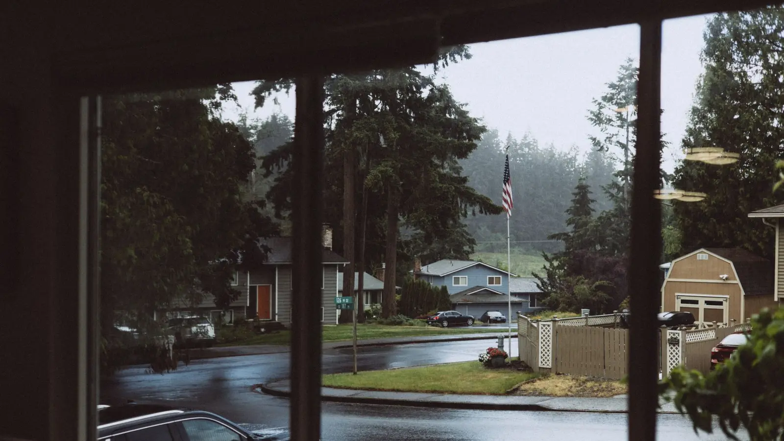 Rainy suburban street and houses seen through a large front window