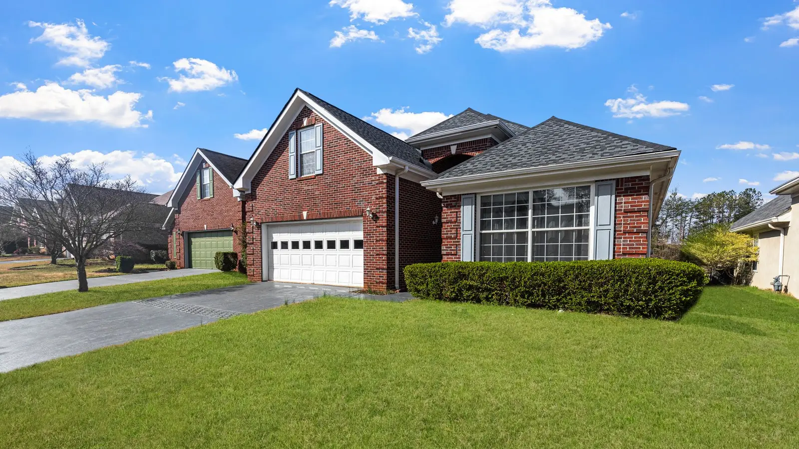 Red brick two-story house with an attached garage and a green front lawn