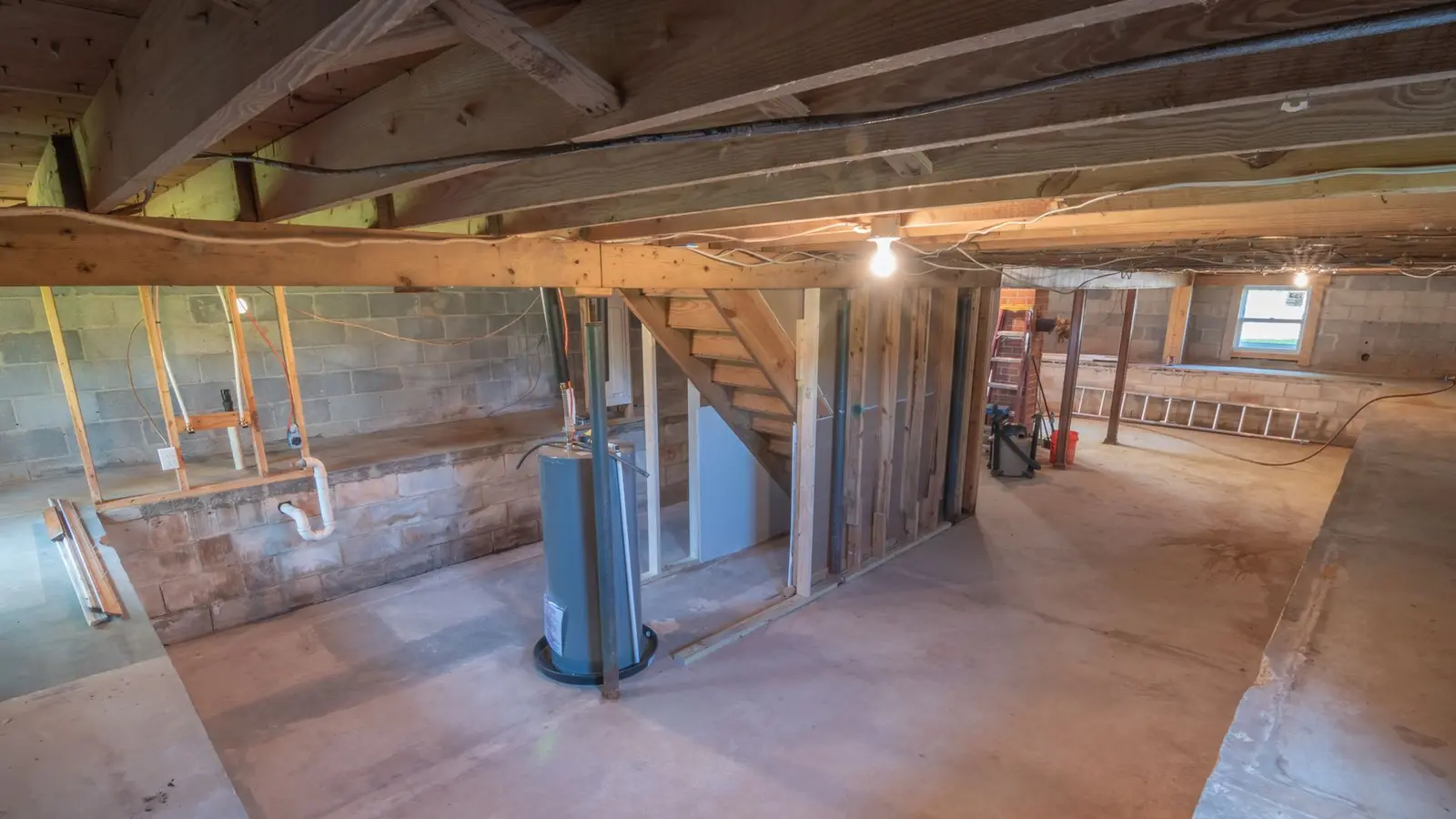 Unfinished basement with exposed plumbing, a water heater and a bare concrete floor